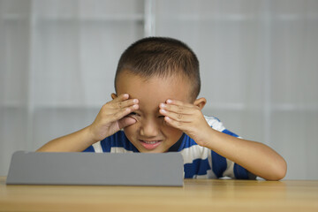 Naklejka premium Boy has eye strain from looking at computer for a long time
