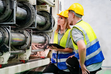 Industrial worker indoors in factory. Young technician with orange hard hat. Smart Caucasian factory worker wearing hardhat and working in power plant.