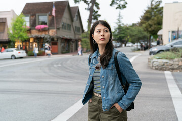 curious asian Taiwanese female visitor looking at her surrounding near the hotel during her stay in the beach town Carmel by the sea California usa