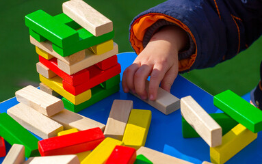  close-up of a child's hand playing wood blocks stack game