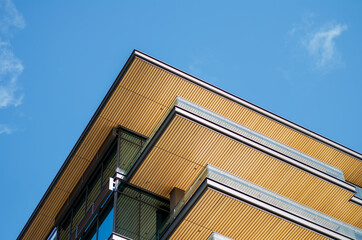 Vertical View of  a Modern Wooden Loft Building Roofline with Blue Sky Overhead.