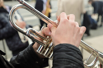 Obraz na płótnie Canvas close-up of the hands of a street musician holding a gold-colored pump-action trumpet 