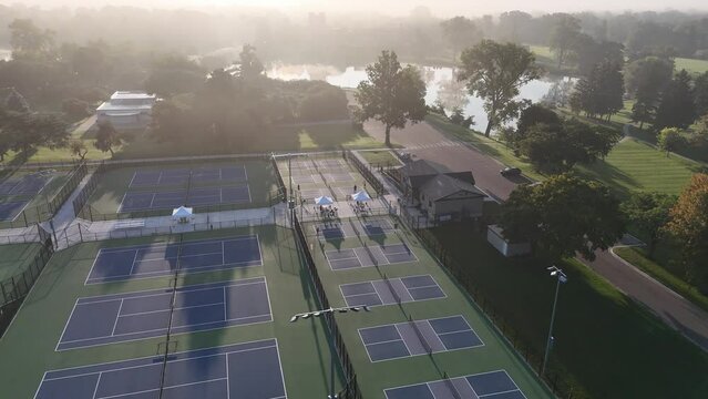 A wide aerial view of couples playing pickleball on a foggy summer morning.  	