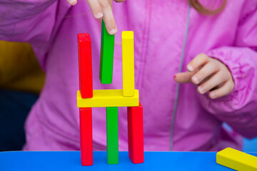 close-up of a child's hand playing wood blocks stack game