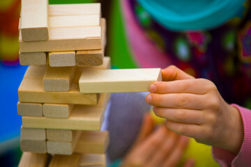 close-up of a child's hand playing wood blocks stack game