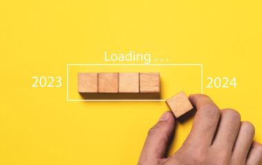 Hand assemble wooden block cube to update progress 2023 to 2024 for countdown and preparation new year change and start new business target strategy concept.