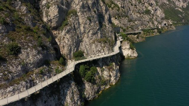 Garda bicycle and pedestrian path suspended above the lake. Alley Limone sul Garda. Section of the longest pedestrian and cycle path in Europe, 4K aerial view. Garda bike path.