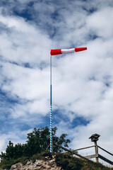 Red and white wind indicator cone with blue sky and clouds in the background