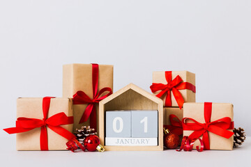 1 january. Christmas composition on colored background with a wooden calendar, with a gift box, toys, bauble copy space