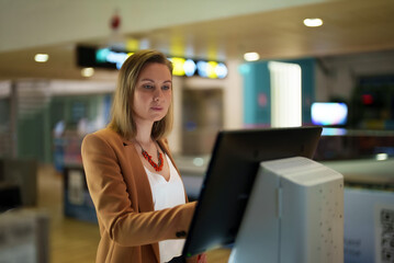 Woman checks her flight at self-service terminal at the airport.