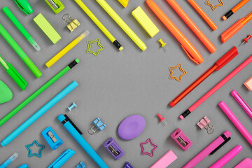 Round frame of colorful rainbow school and office stationery set on gray background. Flatly, copyspace.