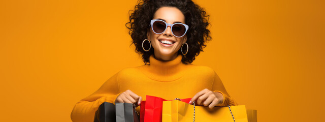 Beautiful attractive smiling woman holding shopping bags posing on yellow background