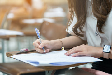 Close-up shot of student's hand writing on paper taking educational admission test in university...