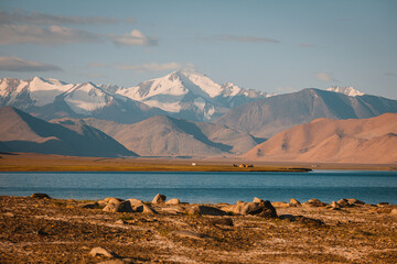 Incredibly beautiful lake Karakul or Karakol. Colorful colors of snowy mountains and sandy hills. Incredible berquoise water of the lake.