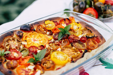 pie baked in the oven with multi-colored tomatoes on top close-up, homemade yeast baking