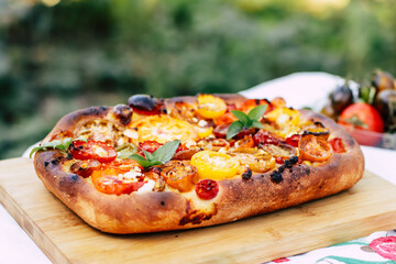 pie baked in the oven with multi-colored tomatoes on top close-up, homemade yeast baking