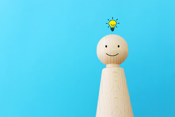 bright light bulb and wooden figure over blue background concept image of