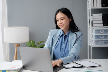 Confident happiness young woman working on laptop or notebook in her office. Beautiful Freelancer Woman working online at her home. Beauty Asian business woman concept.