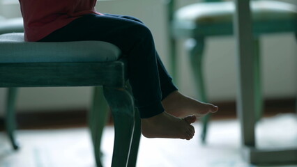 Child legs and feet seated on chair, cute small boy waiting for food at diner table at home