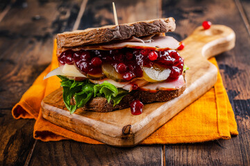 Homemade leftover thanksgiving day sandwich with turkey, cranberry sauce and vegetables. Dark rustic style