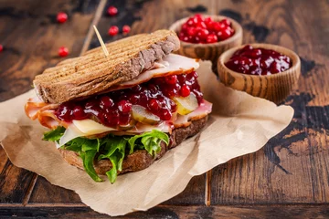 Foto op Canvas Homemade leftover thanksgiving day sandwich with turkey, cranberry sauce and vegetables. Dark rustic style © happy_lark