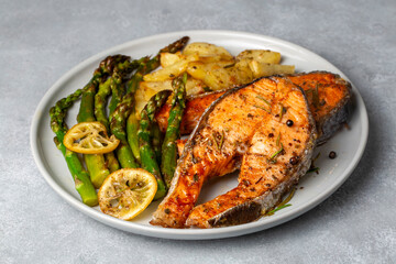 Grilled, baked salmon served on a plate with asparagus and potatoes.