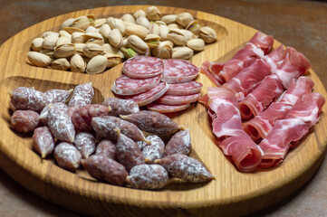 Wooden tray with sausages, pistachios and prosciutto