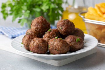 Round shaped balls of dry meatballs and french fries. Turkish name; kuru kofte ve patates