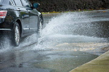 a car driving through the puddle and splashing water in a raining day