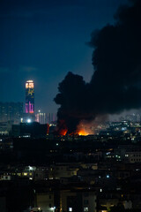 a factory catched a fire with lots dark smoke at night vertical composition