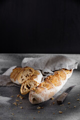 French baguette on a cotton towel on a grey background close-up. Free space for text