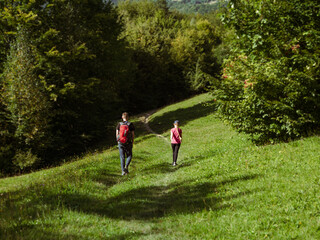 Family walks on trail green lawn Zakarpattya village Carpathian mountains view, Ukraine Europe...