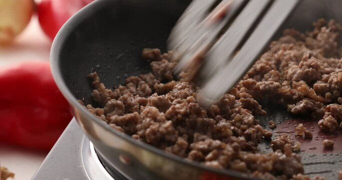 Man frying minced meat in a frying pan stirring with a spatula. Close-up. Cooking bolognese sauce. Food preparation in the kitchen. A series of footage to visualize the recipe.
