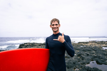 Fototapeta premium happy surfer in the coast with his red surfboard