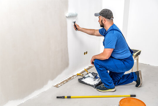 Builder painting the wall with painting roller in white color