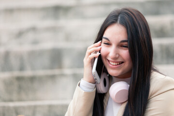 girl on the street listening to music with pink headphones and calling on the phone and sending messages