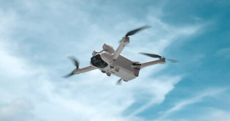 Drone Copter is filming in air. Modern quad copter drone on sky background. The concept of filming video and photos while traveling on quadcopter drone. Modern robot drone in slow motion - Powered by Adobe