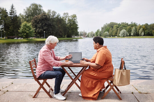 Side view portrait of two senior people man and woman talking duing business meeting at table in outdoor cafe