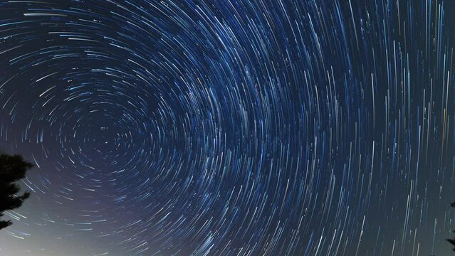 Star trail of stars moving in the night sky around the North Star. Landscape with movement of stars in the Tuscan country, time lapse