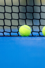 selective focus, two balls near the net in a blue paddle tennis court. Racket sports concept