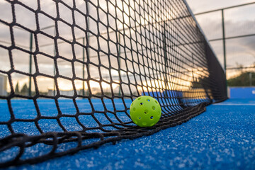 Selective focus. A pickleball ball on the net at sundown