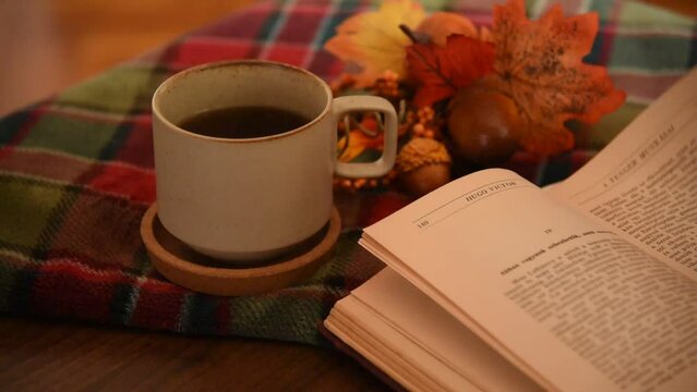 Turning the pages of a book in a cozy autumn decor with candles 