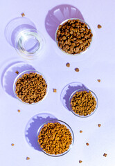 A composition of different types of dry food laid out in glass bowls and water. On a purple background..water. Style, modern, contemporary - 646927768
