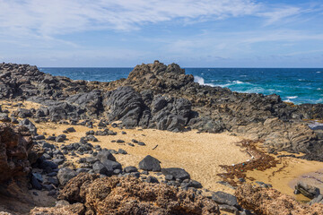 Fototapeta na wymiar Beautiful view of rocky coastline and blue water waves of Caribbean sea. Aruba.