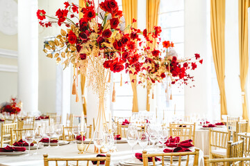 Floral arrangement, festive bouquet, table decoration for Chinese New Year party celebration in restaurant. Traditional red gold color decor. Roses,poppies,fan,candles,tassels. Chinese lunar calendar