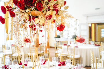 Floral arrangement, festive bouquet, table decoration for Chinese New Year party celebration in restaurant. Traditional red gold color decor. Roses,poppies,fan,candles,tassels. Chinese lunar calendar