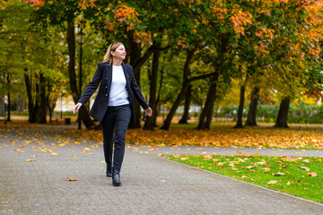 Fototapeta premium Beautiful businesswoman walking in city park 