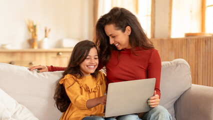 Joyful Eastern Mom And Daughter Using Laptop At Living Room