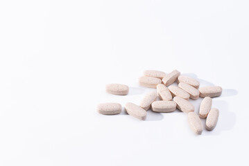 Pile of speckled, oblong, tablets on a white background.  Glucosamine chondroitin dietary supplements on a white background.