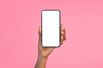 Hand of millennial black lady show smartphone with blank screen, isolated on pink background, studio, close up
